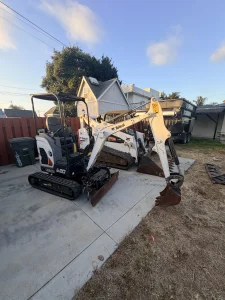 Bobcat E20 mini excavator parked in a fenced residential backyard in San Diego