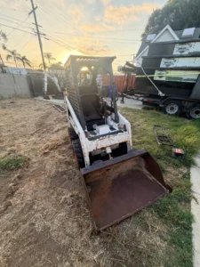 Bobcat S70 mini skid steer with a smooth-edge bucket in a San Diego residential backyard