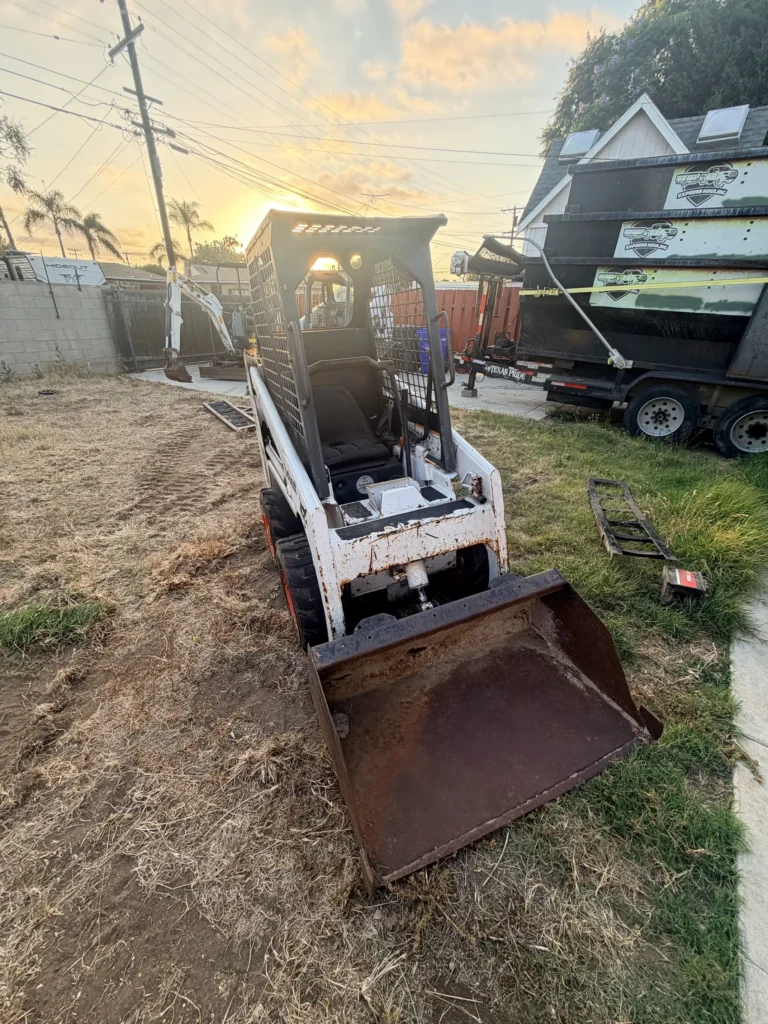 Bobcat S70 mini skid steer with a smooth-edge bucket in a San Diego residential backyard