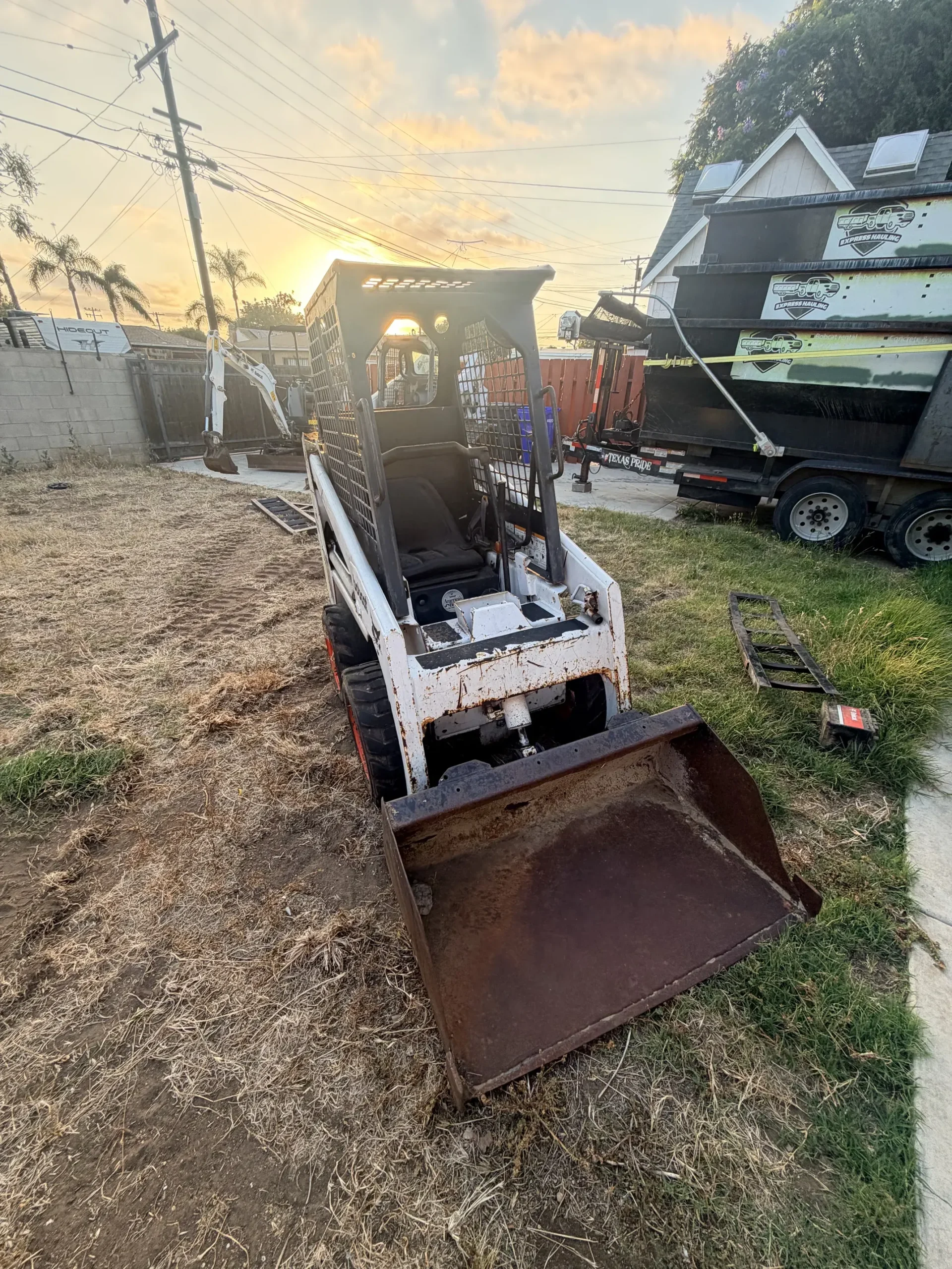 Bobcat S70 mini skid steer with a smooth-edge bucket in a San Diego residential backyard