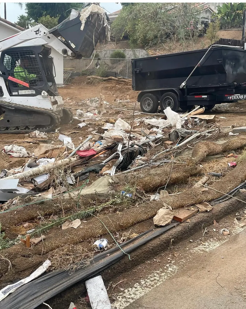 Bobcat T770 loading construction and yard debris into a dump trailer on a San Diego job site