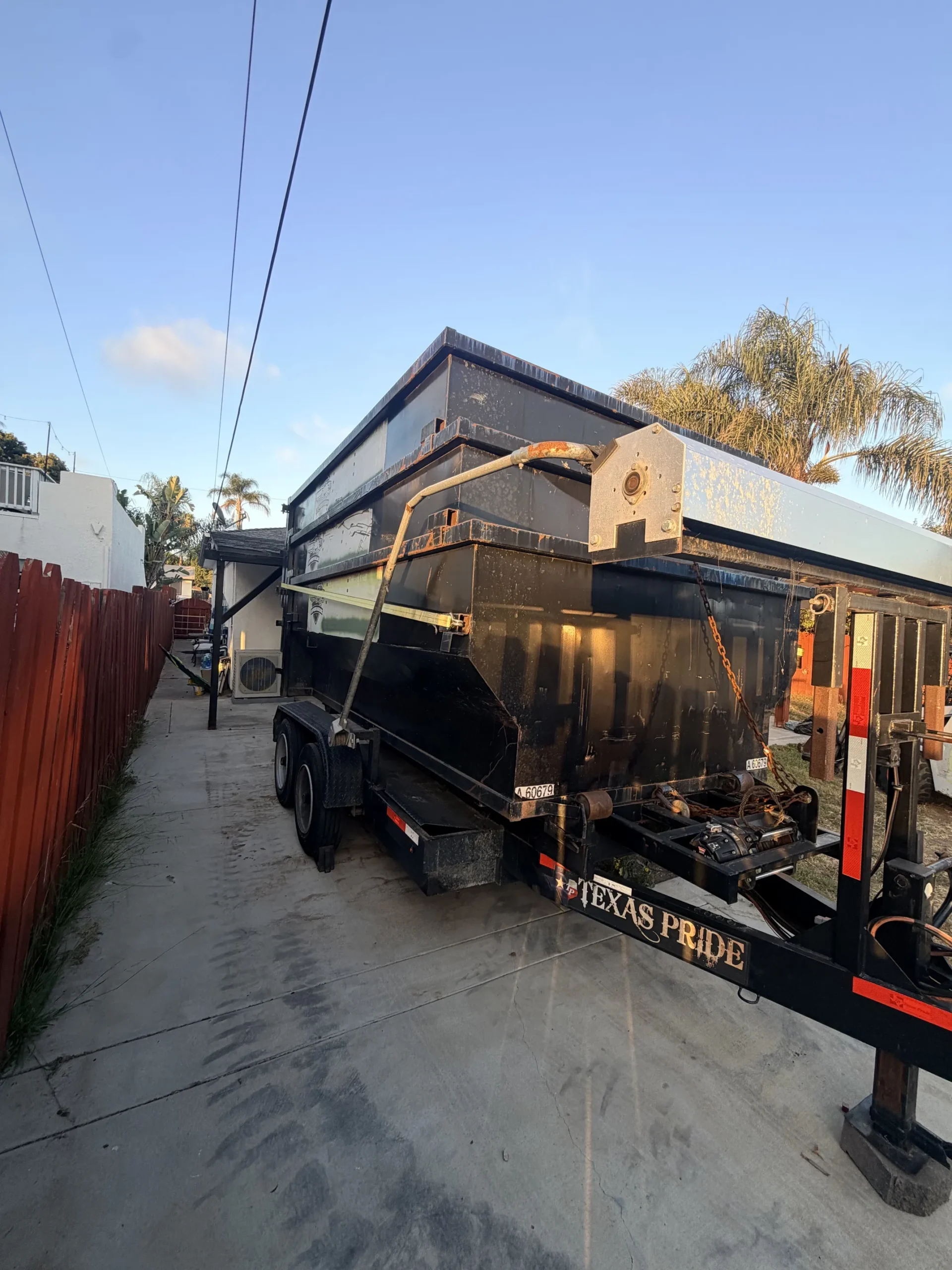 Roll-off container and Bobcat T770 staged at a new home construction site in San Diego
